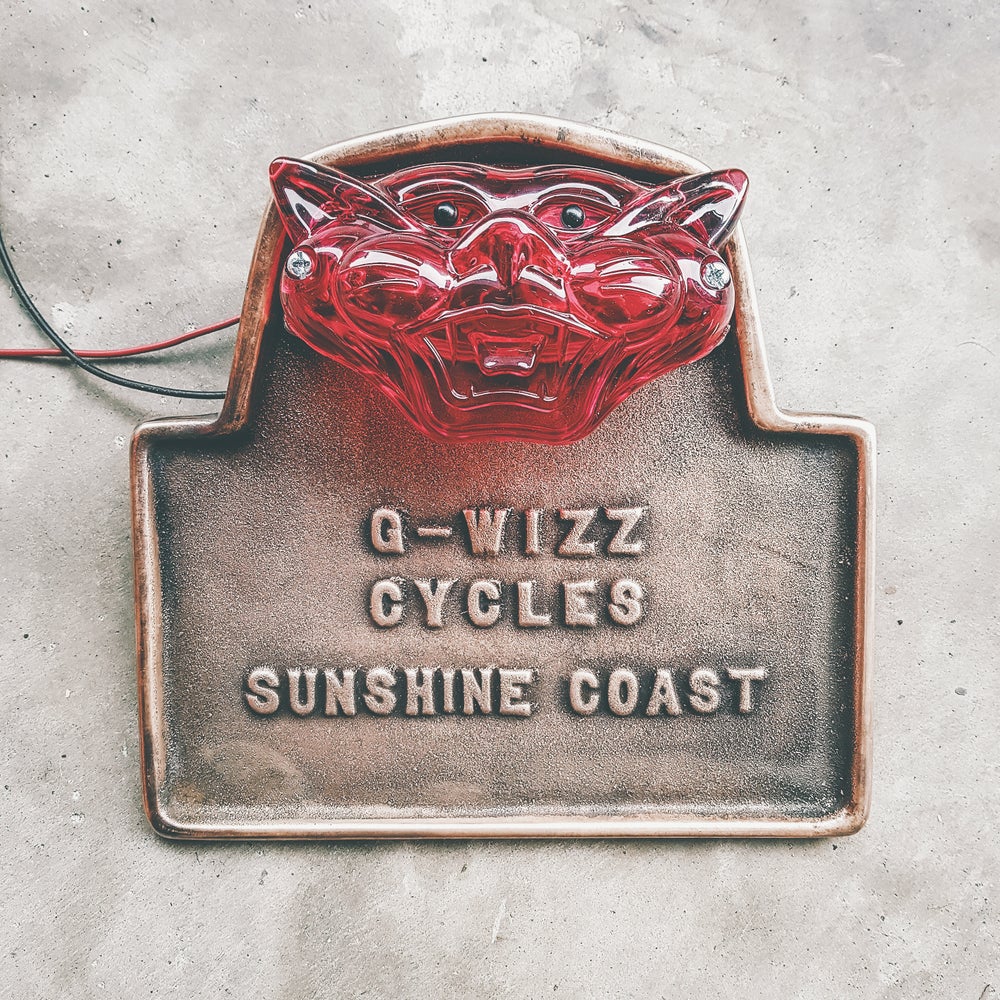 Front view of G-Wizz Cycles Cast Brass Taillight holder with a patina finish and cat face taillight mounted